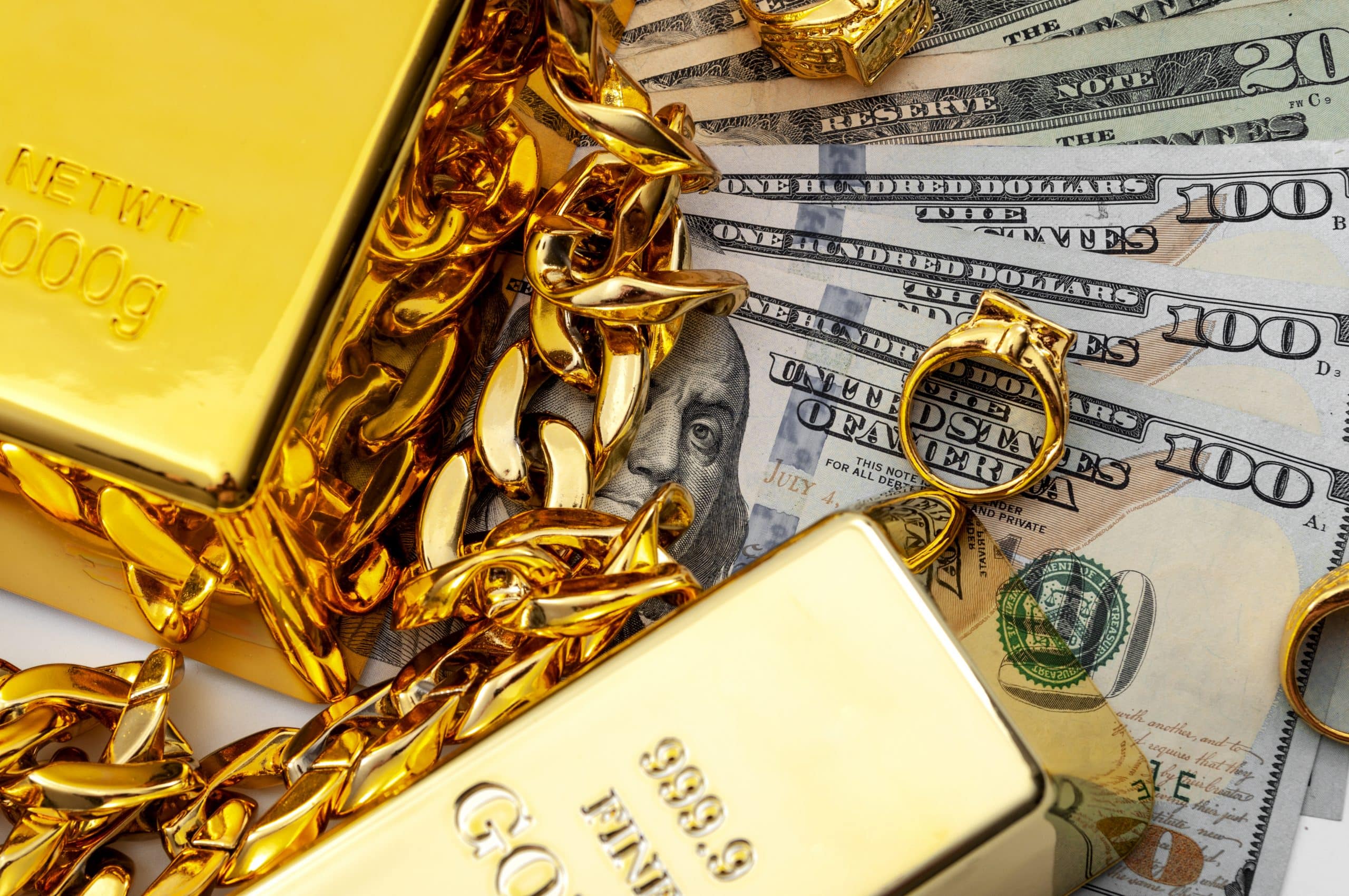Jewelry buyer, pawn shop and buy and sell precious metals concept theme with a pile of cash in US dollars, golden rings, necklace bracelet and gold bullion isolated on white background